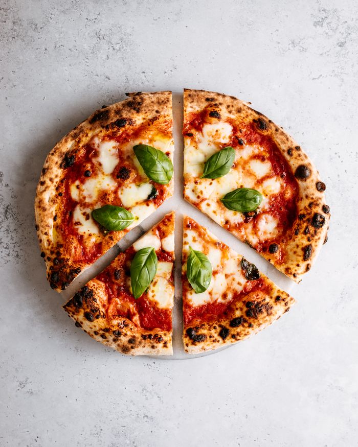 Top view of a classic Margherita pizza with fresh basil on a marble background.
