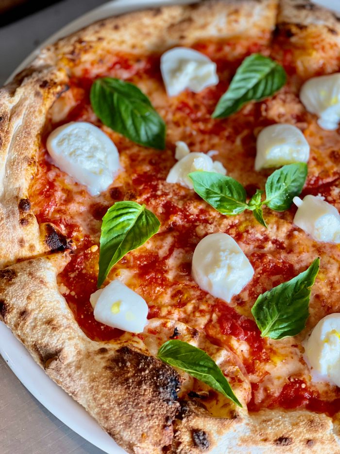 Freshly baked Margherita pizza topped with mozzarella and basil leaves, perfect for a tasty meal.