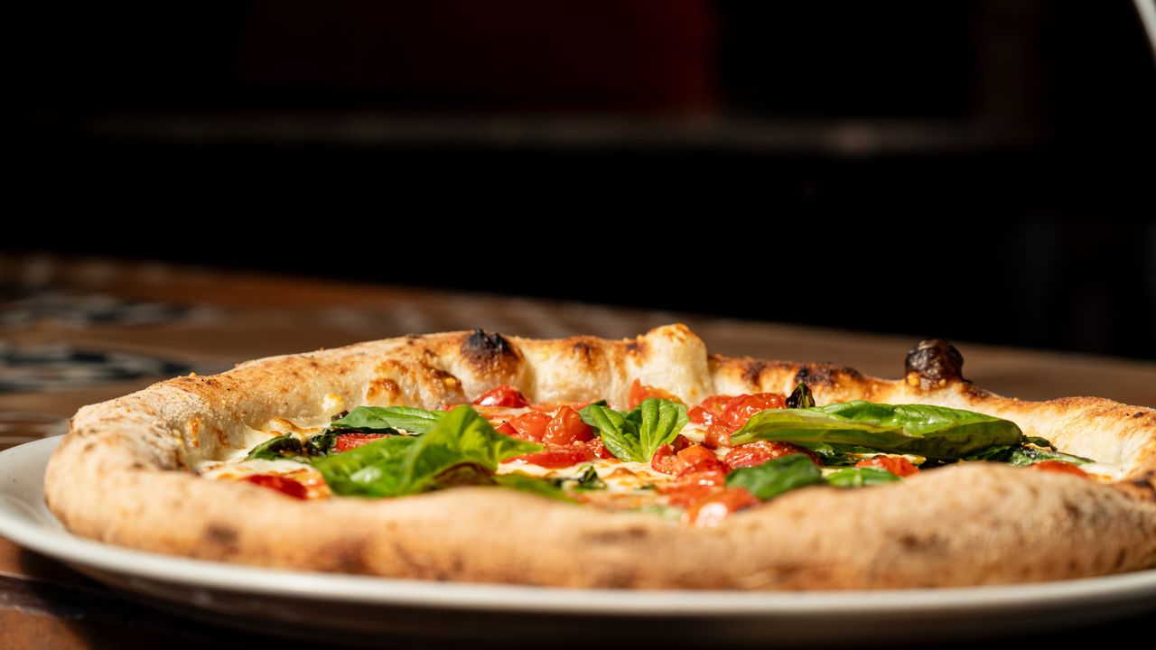 Delicious Margherita pizza with fresh basil and tomatoes in a cozy setting.