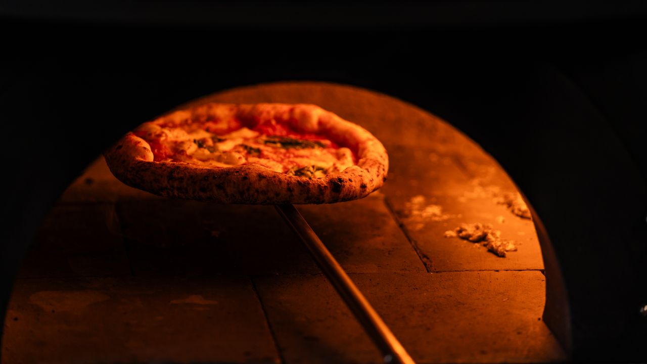 Delicious Neapolitan pizza baking in a rustic wood-fired oven, capturing the essence of traditional pizza making.